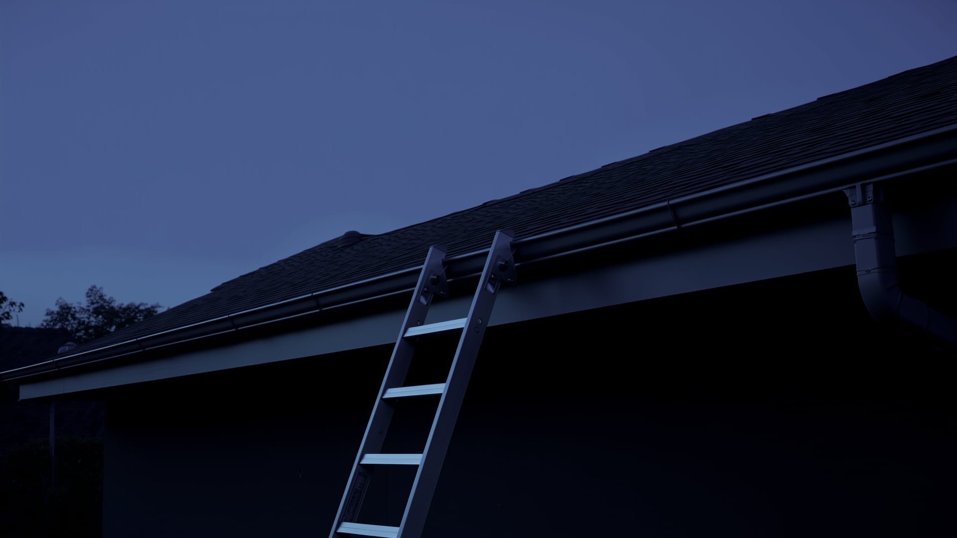 A newly installed seamless gutter run along a residential roofline at dusk