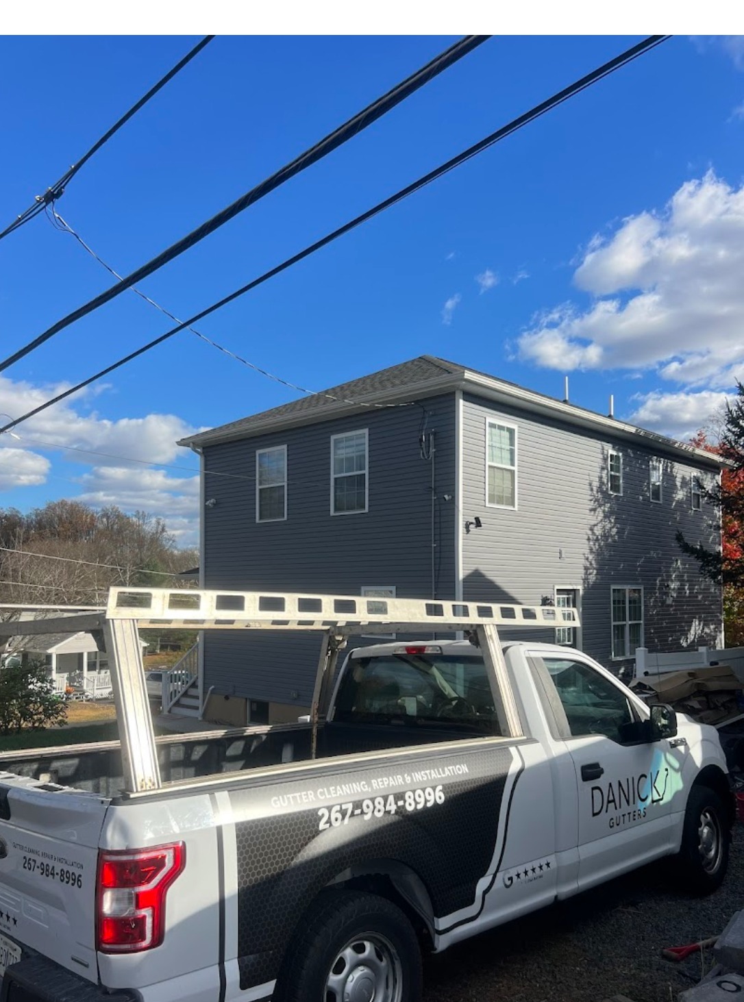 Danick Gutters truck with ladder rack parked at a residential job site