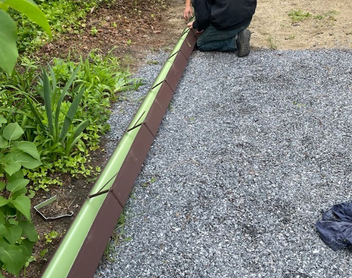 Downspout extension routing roof water away from the foundation into gravel