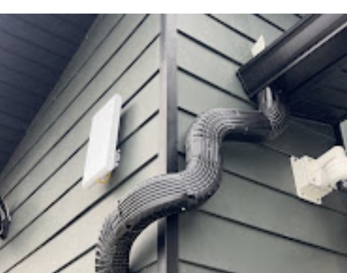 Downspout elbow neatly strapped to gray siding after repair