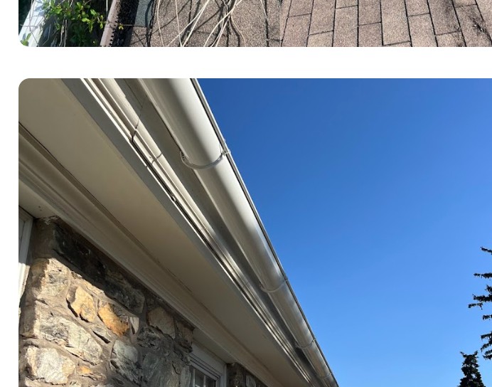 Newly installed gutter running along a stone home under blue sky