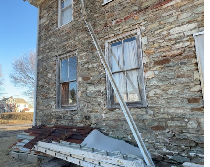 Seamless gutter installation in progress on a stone farmhouse